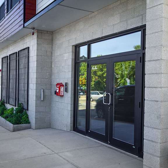 a person is walking past a building with a glass door and a red fire extinguisher on the wall.